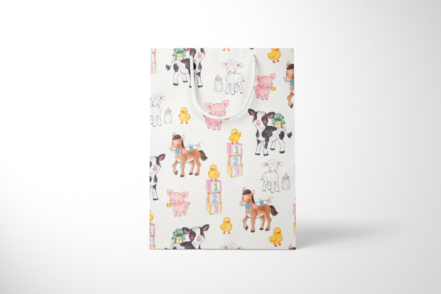 Front view of light cream gift bag featuring a whimsical pattern of baby farm animals, including cows, pigs, lambs, ducklings, and ponies, surrounded by baby bottles, gift boxes, and pastel alphabet blocks, with white rope handles.