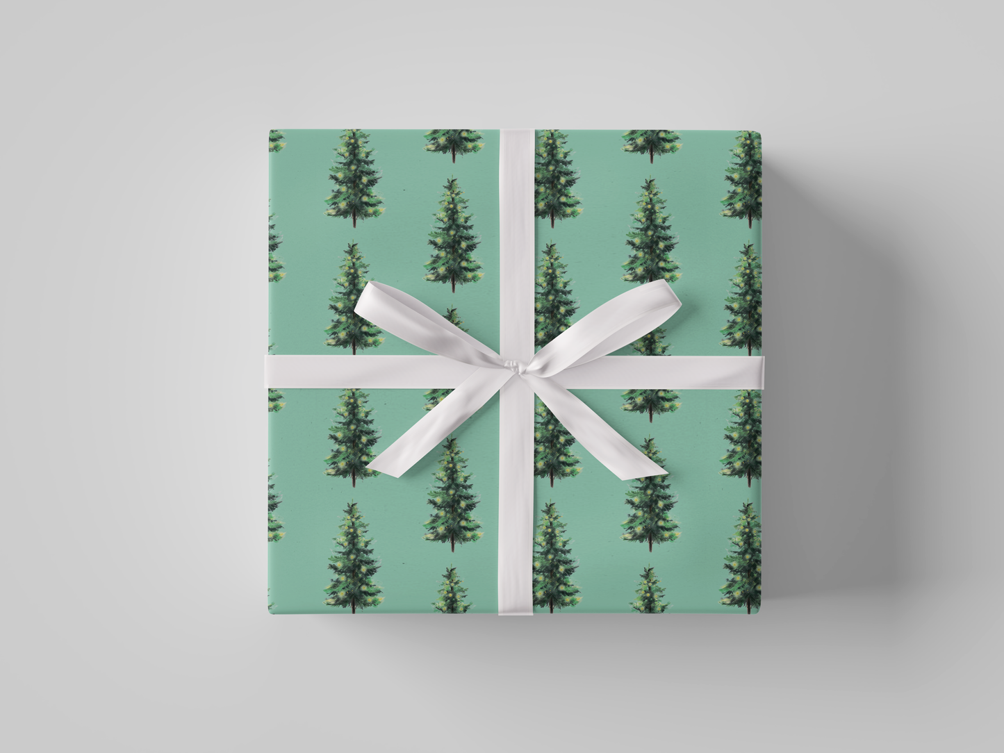 Front view of Christmas wrapping paper featuring dark green Christmas trees with glowing yellow lights on mint green background