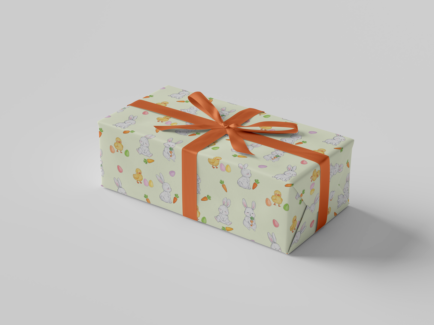 Side view of light yellow Easter wrapping paper showcasing white bunnies, yellow baby chicks, carrots, and pastel-colored eggs.