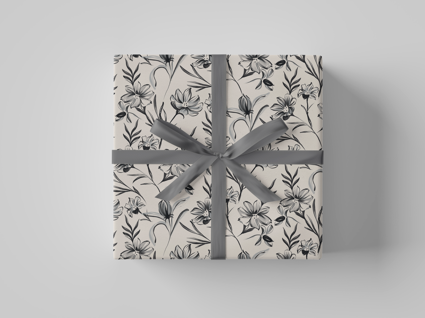 Top view of cream floral-patterned wrapping paper with black , cream and gray flowers and leaves.