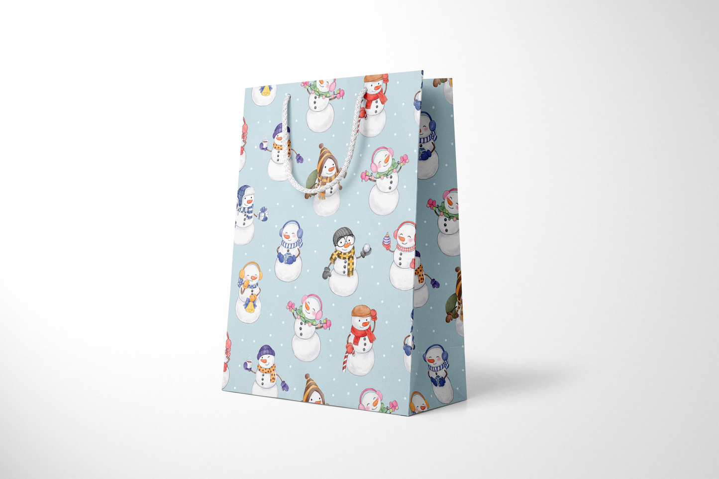 Side view of light blue gift bag with a whimsical snowman pattern, featuring snowmen in colorful scarves, hats, and earmuffs, holding holiday items like gifts, candy canes, and hot cocoa, with white rope handles and scattered snow dots and a white rope handles.