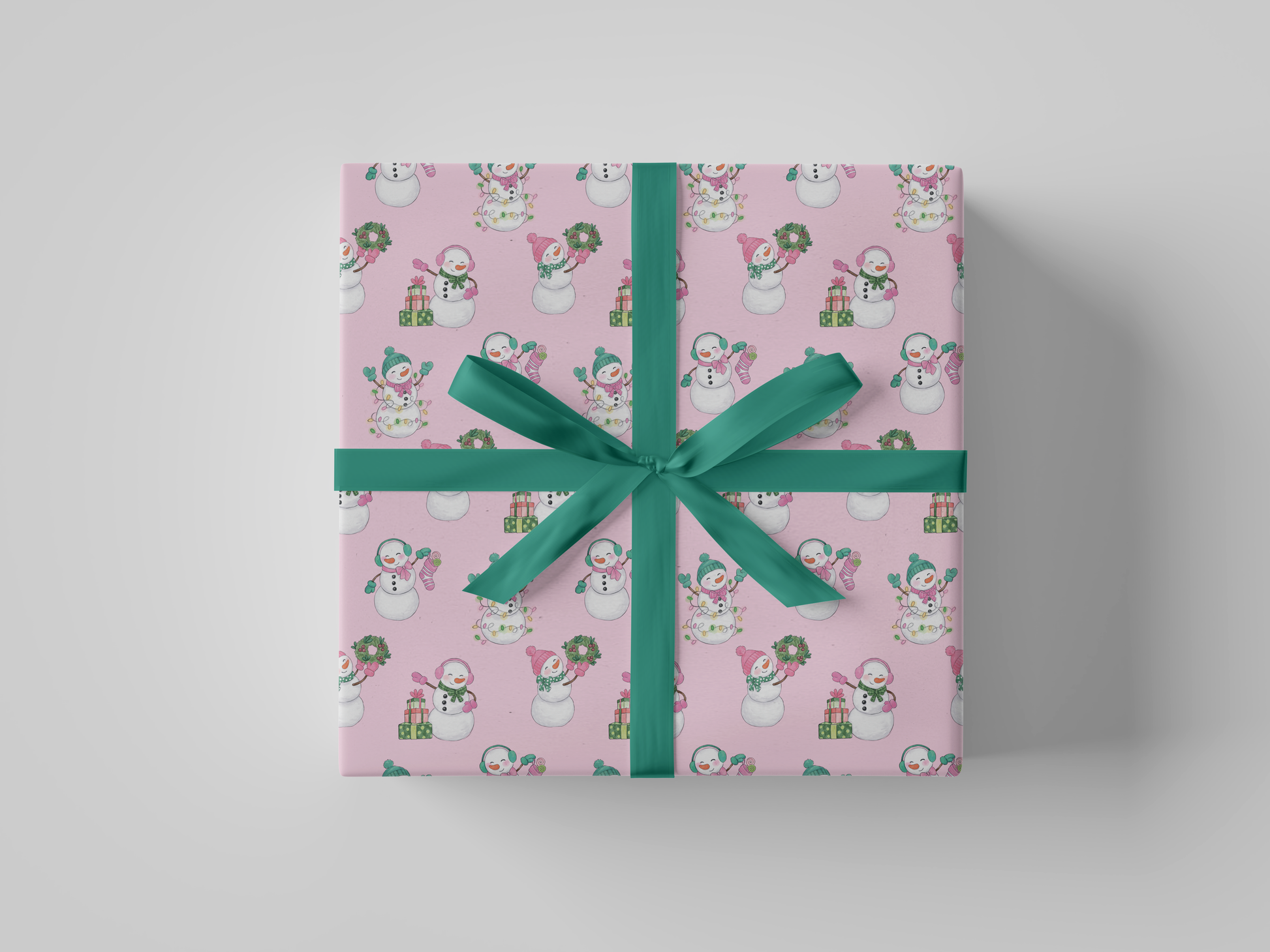 Front view of pink-colored wrapping paper featuring pink and green snowladies holding Christmas gifts, stockings, wreaths, and Christmas tree lights.