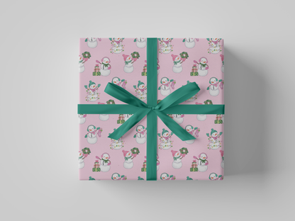 Front view of pink-colored wrapping paper featuring pink and green snowladies holding Christmas gifts, stockings, wreaths, and Christmas tree lights.