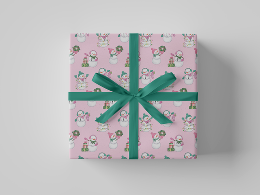 Front view of pink-colored wrapping paper featuring pink and green snowladies holding Christmas gifts, stockings, wreaths, and Christmas tree lights.