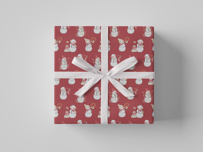 Front view of red-colored wrapping paper featuring red and white snowladies holding Christmas gifts, stockings, wreaths, and Christmas tree lights.