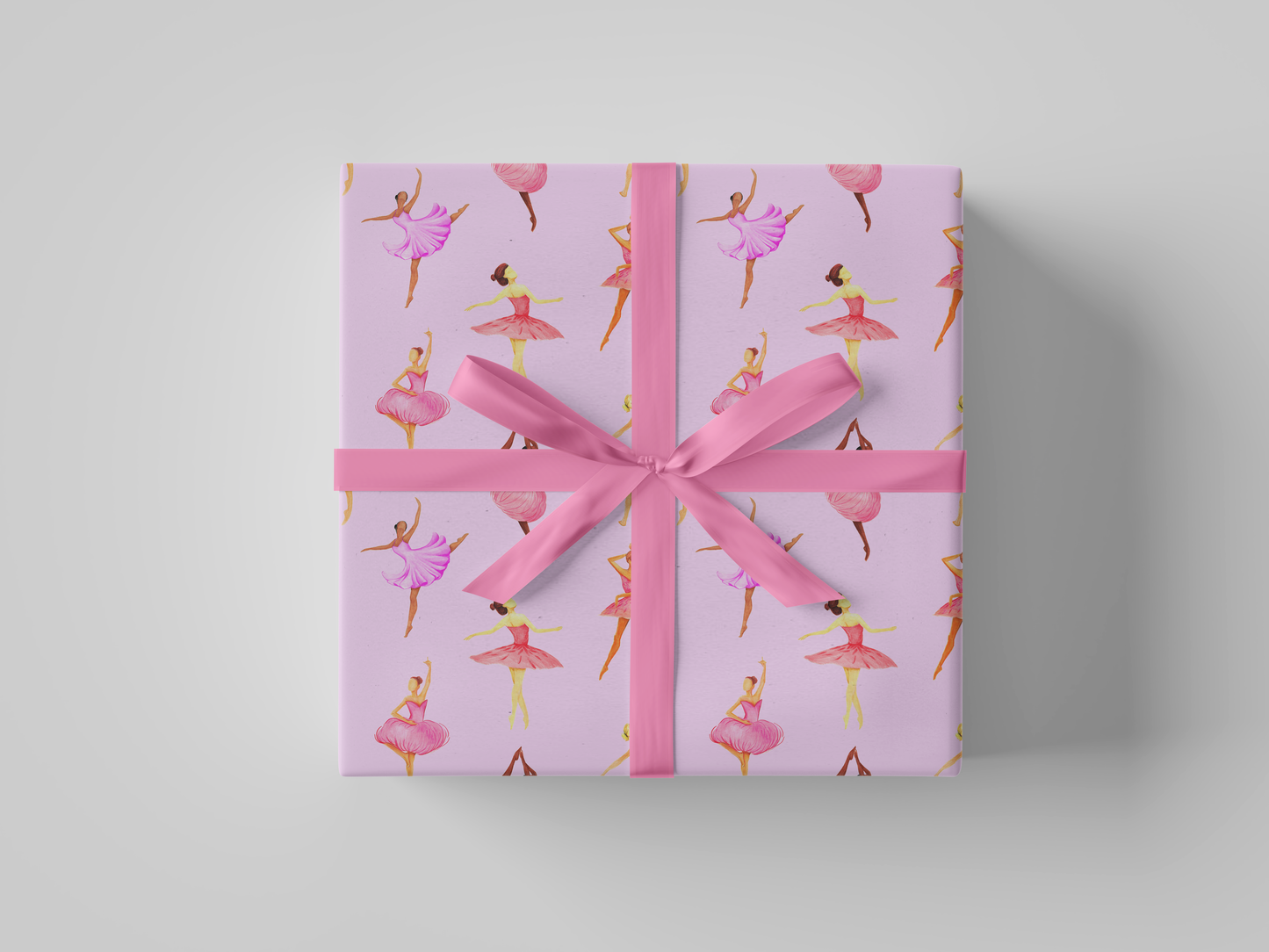 Front view of pink ballerina wrapping paper featuring dancers in pink and purple tutus posed against a soft pink background