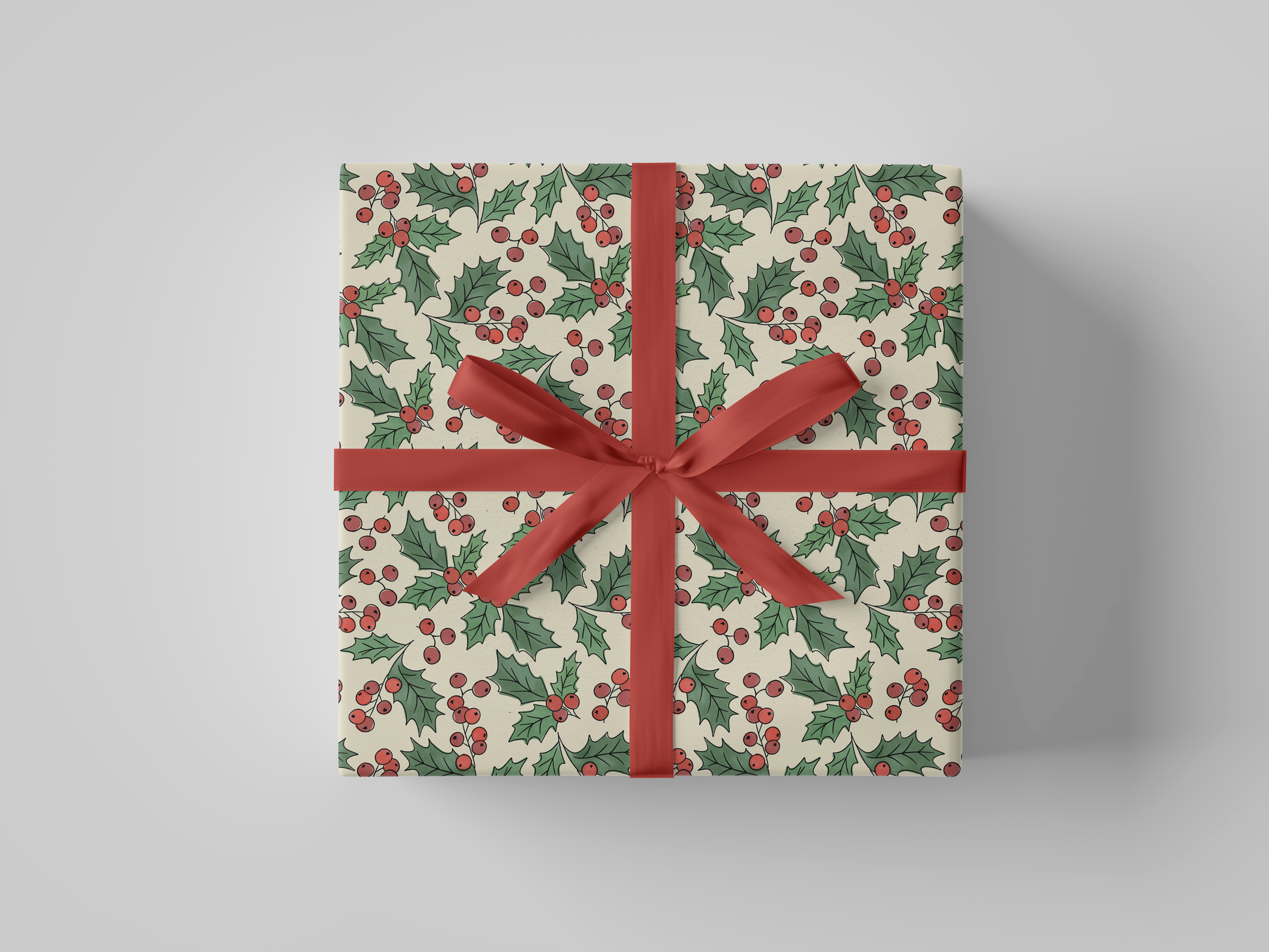 Front view of cream-colored wrapping paper adorned with Christmas holly, showcasing red berries and green leaves.
