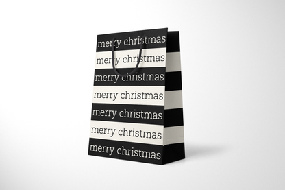Side view of modern minimalist gift bag featuring alternating black and cream stripes with repeating ‘merry christmas’ text in bold typography, finished with sturdy black rope handles.