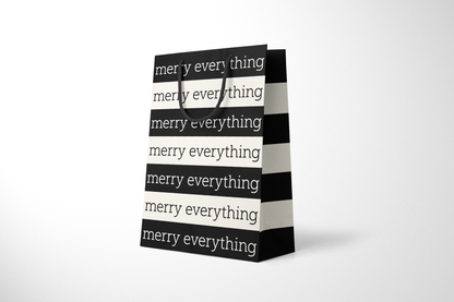 Side view of modern minimalist gift bag featuring alternating black and cream stripes with repeating ‘merry everything’ text in bold typography, finished with sturdy black rope handles.